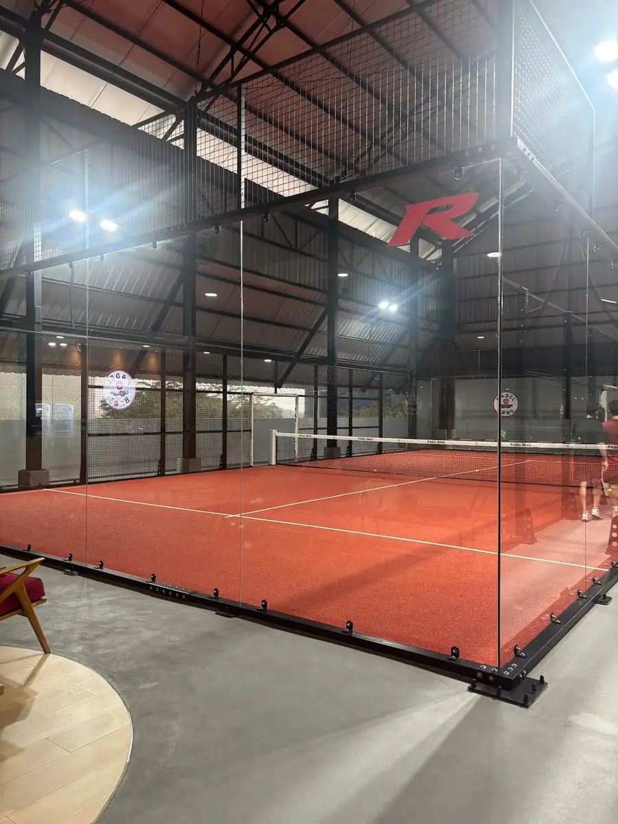 Panoramic glass court with clay-red turf