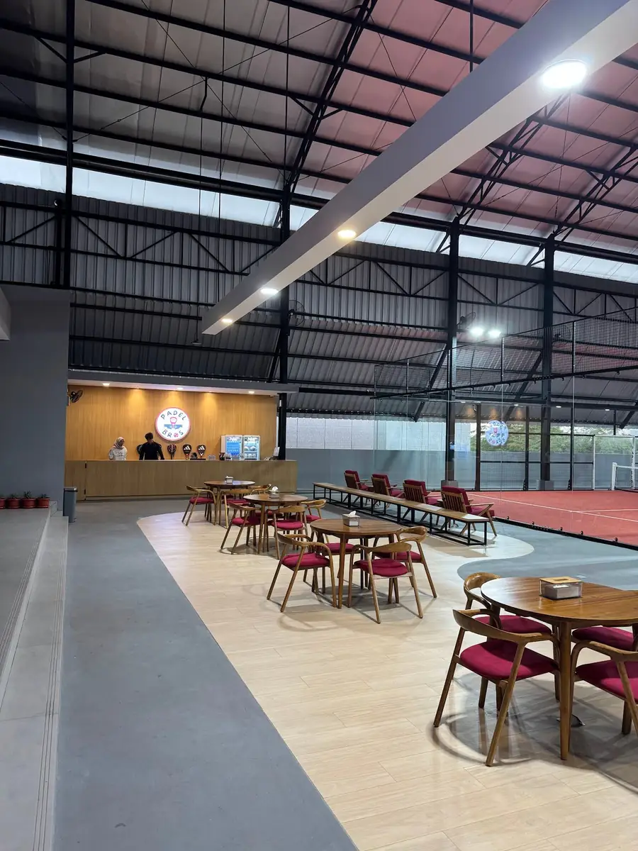 Courtside lounge with walnut tables and red-velvet chairs